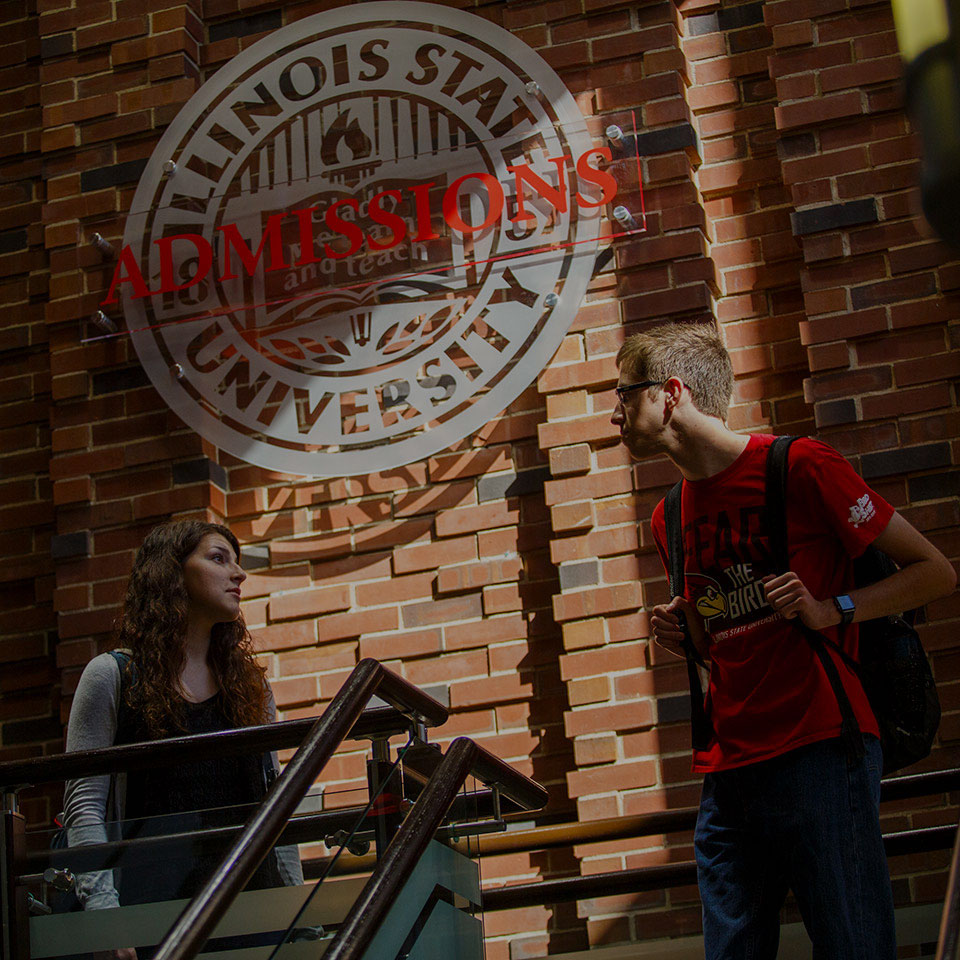 Two students standing in front of the Admssions sign.