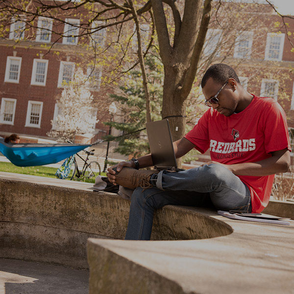 Student sitting on a concrete bench on the quad.