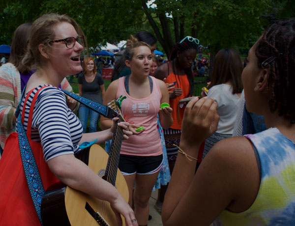 A group of students playing instruments and singing on the quad.